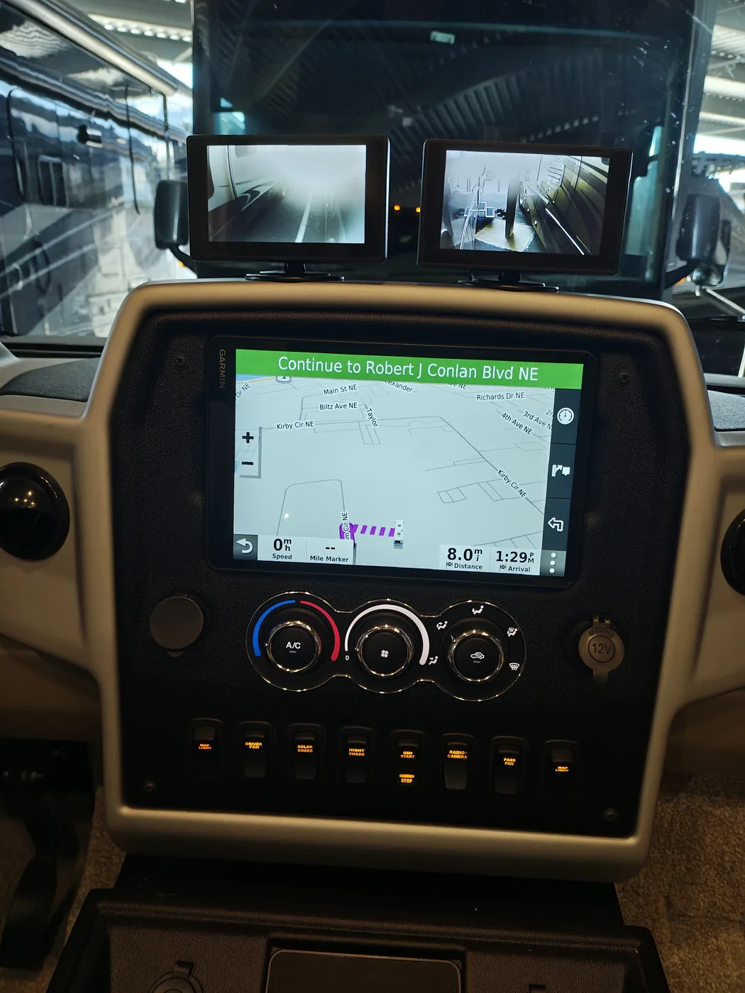 Both side camera monitors displaying video while Garmin navigation remains visible